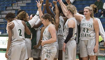 Shelton State Women's Basketball team with arms in the air