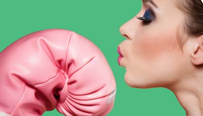 woman kissing pink boxing glove on green backdrop