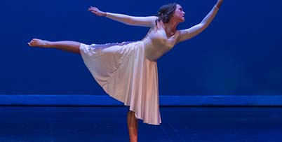 Dancer in log satin dress on blue backdrop