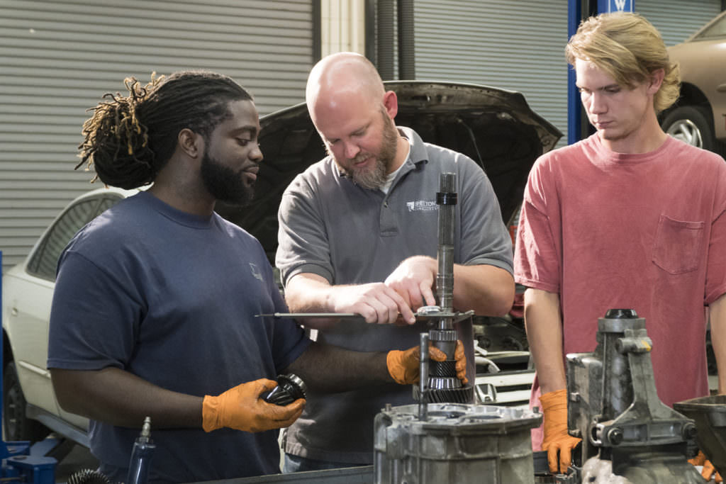 Teacher works on engine with two students